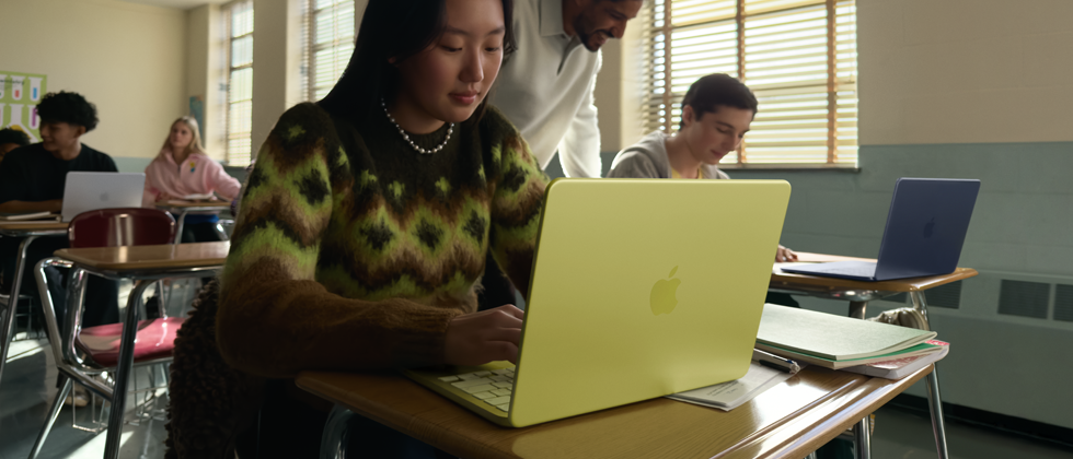 Una estudiante usa una MacBook Neo, color amarillo cítrico, sin enchufar a la corriente en un salón de clases