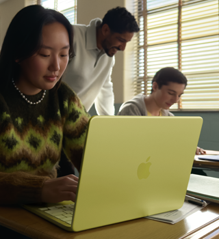 Una estudiante usa una MacBook Neo, color amarillo cítrico, sin enchufar a la corriente en un salón de clases
